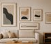 Minimalist tarzda döşenmiş bir oturma odasında duvarda asılı farklı boyutlarda modern sanat tabloları